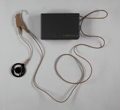 Un boîter rectangulaire avec un long fil jusqu'au contour d'oreille avec une antenne.