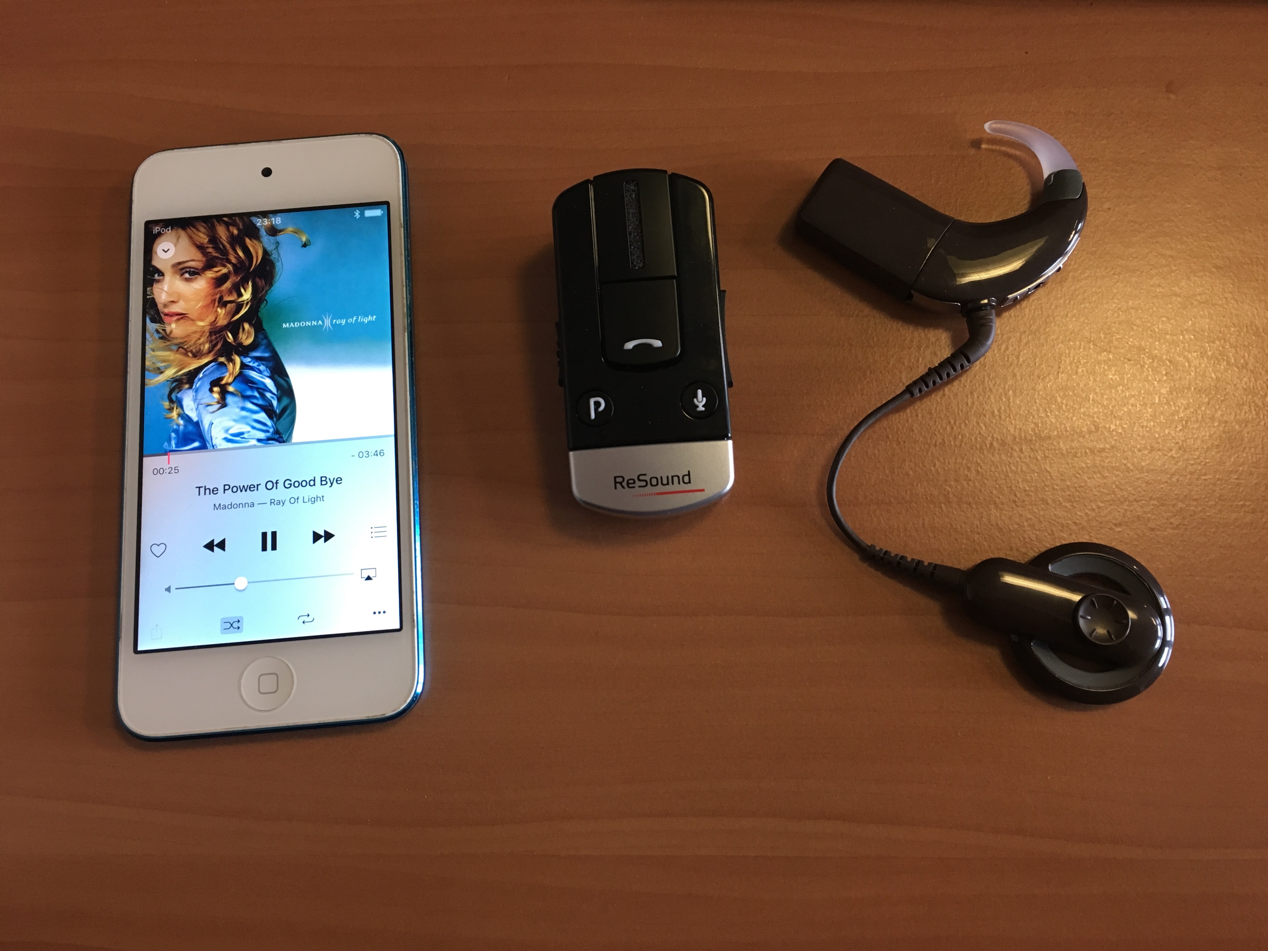 A gauche, mon IPod montrant la chanson en cours The Power of GoodBye de Madonna. Au milieu, le mini-mic Resound avec des boutons. A droite, mon implant cochléaire.